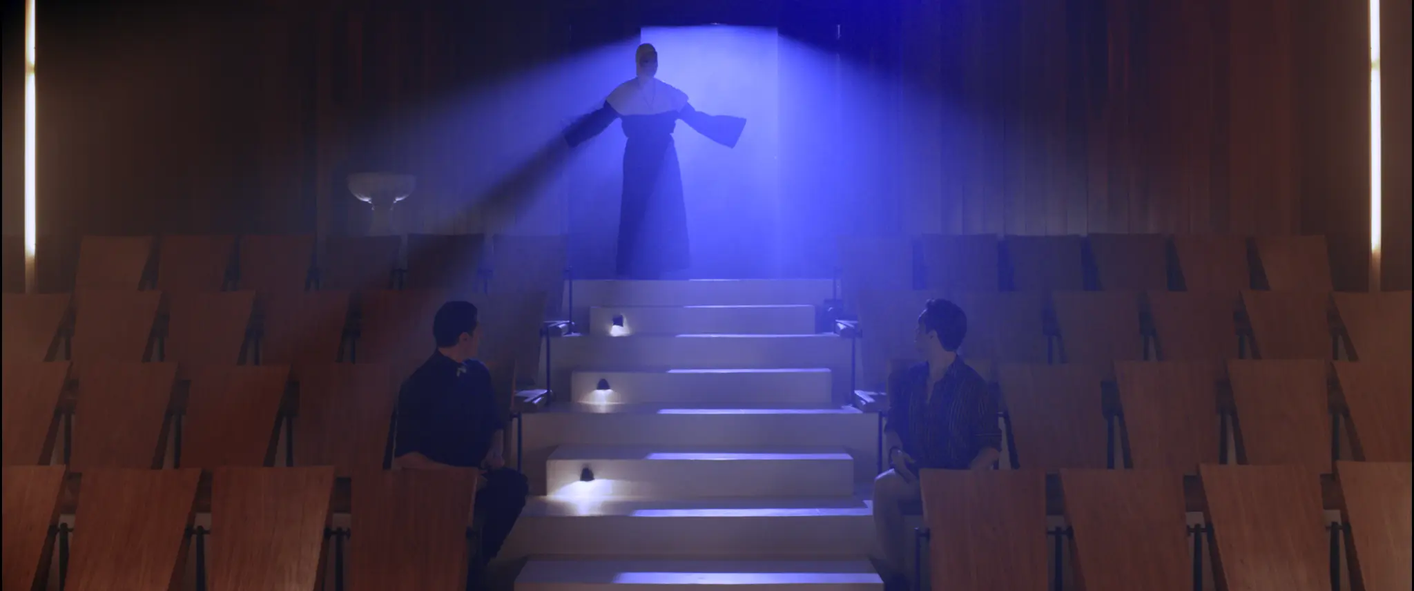 Figura iluminada em azul no alto de uma sala de cinema