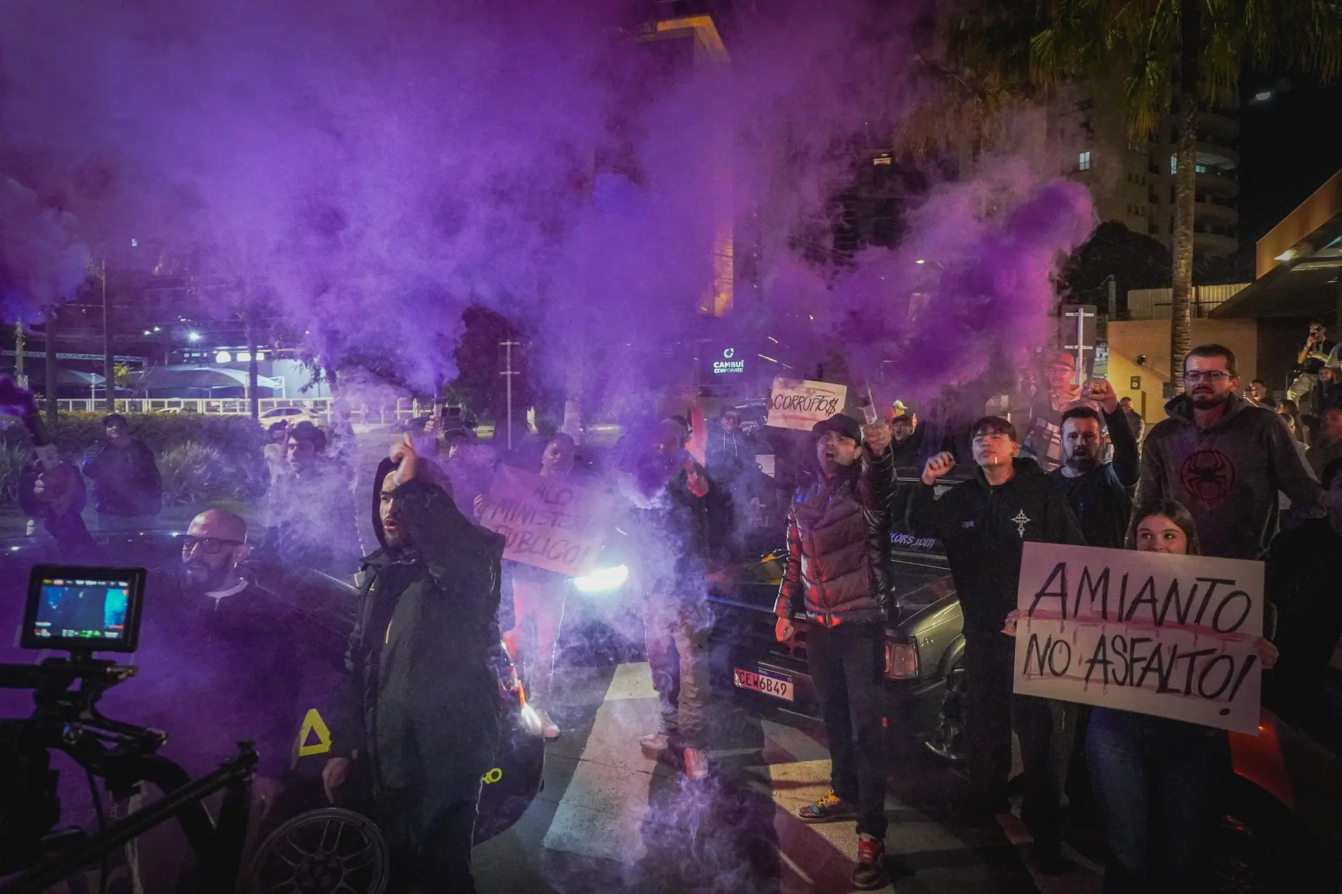 Bastidores de Asfalto com manifestação e fumaça roxa