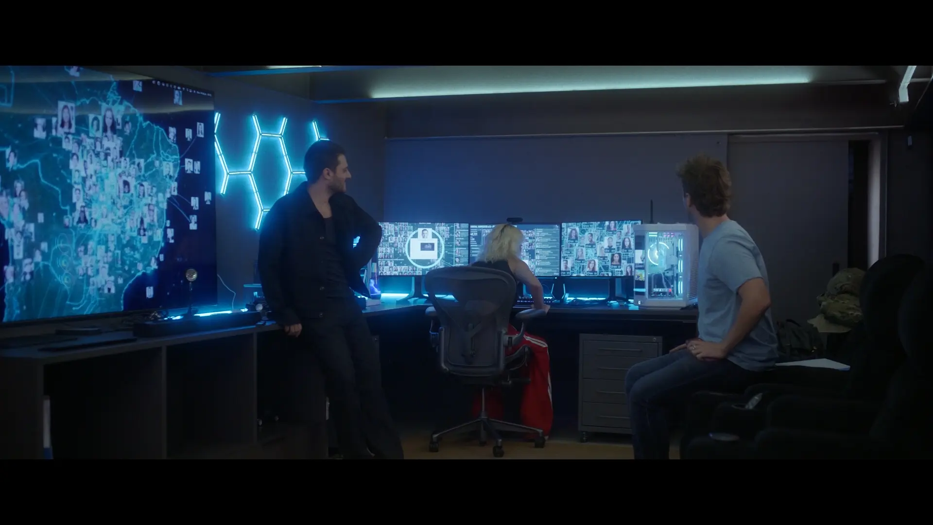 Personagens observam telas em uma sala de monitoramento